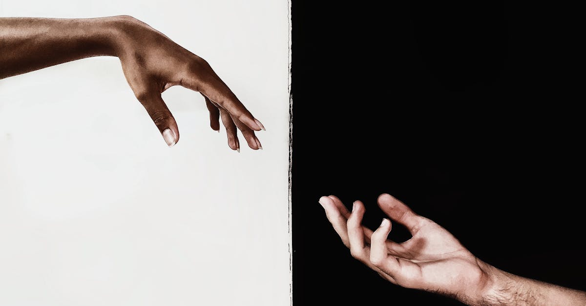 Two hands reaching across a stark black and white divide, symbolizing connection and unity.